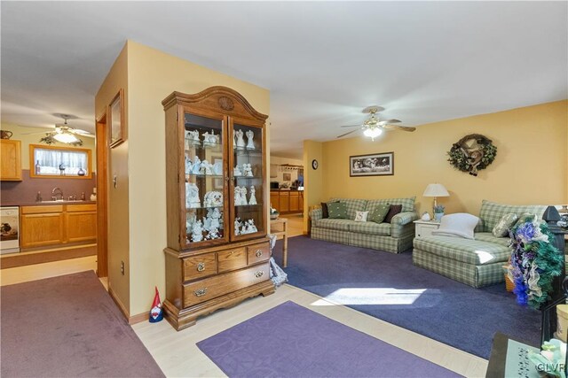 living area with a ceiling fan, bar with sink, and light carpet
