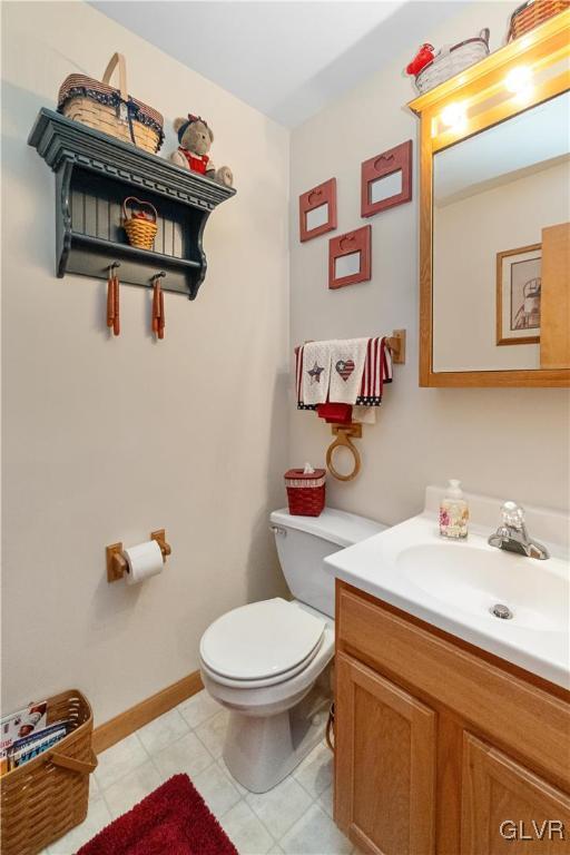 bathroom featuring toilet, vanity, and baseboards