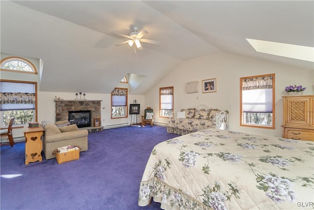 carpeted bedroom with ceiling fan, a stone fireplace, multiple windows, and vaulted ceiling with skylight