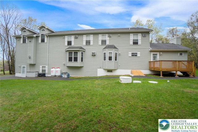back of house with a deck, a yard, and a chimney