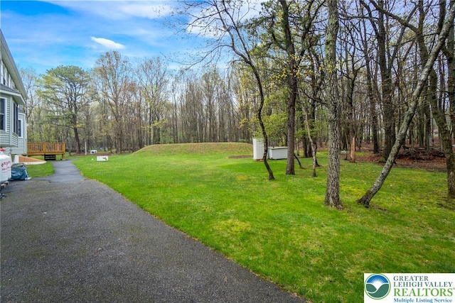 view of green lawn featuring a wooden deck