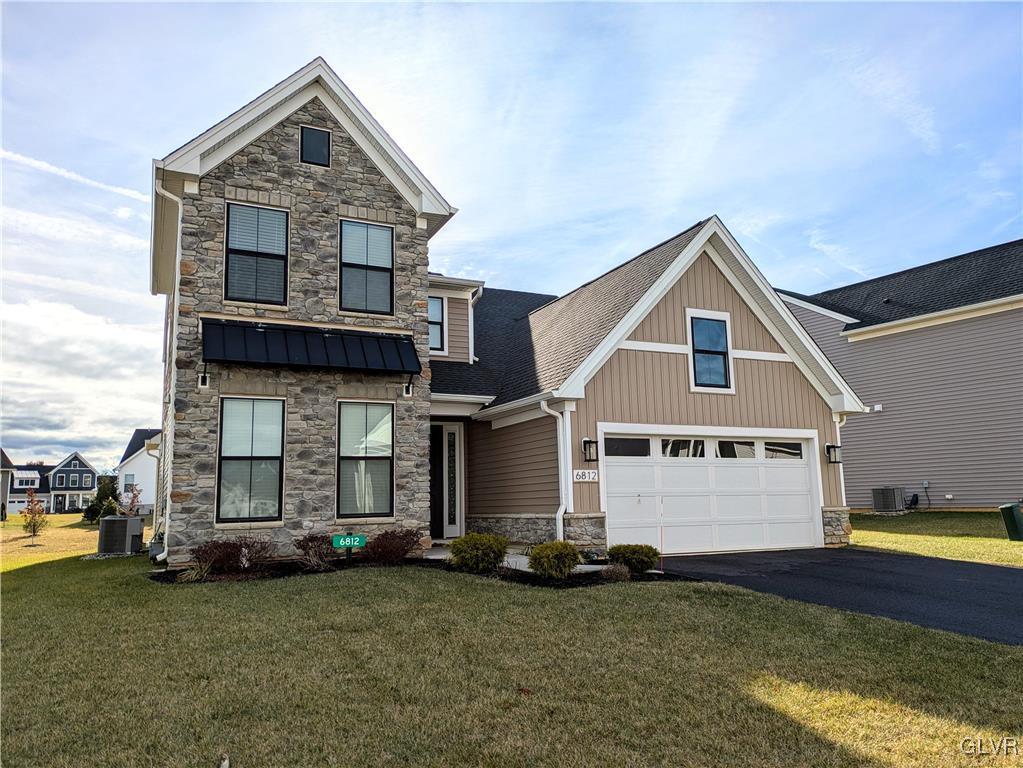 craftsman-style home with a front yard, a garage, and central air condition unit