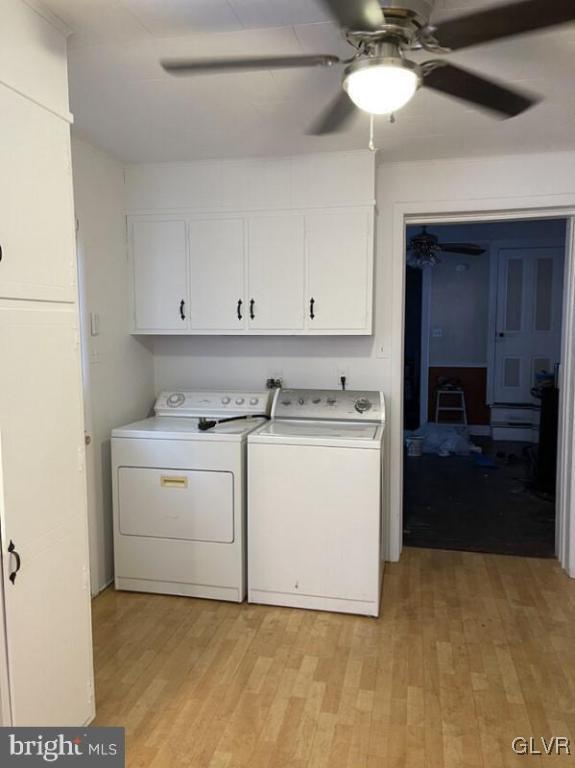 washroom featuring cabinets, independent washer and dryer, and light hardwood / wood-style flooring