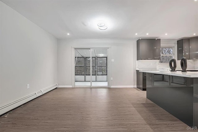 kitchen featuring backsplash, a baseboard radiator, hardwood / wood-style flooring, and a breakfast bar area