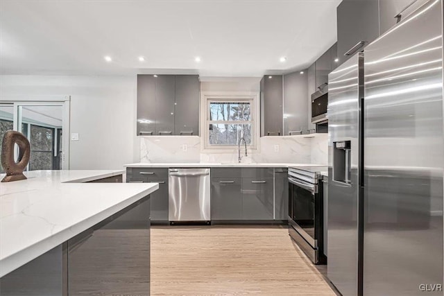 kitchen with backsplash, gray cabinetry, sink, and appliances with stainless steel finishes