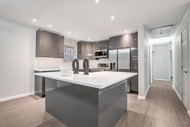 kitchen with stainless steel appliances, backsplash, an island with sink, a kitchen bar, and gray cabinets