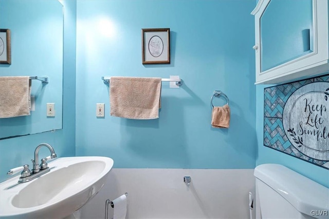 bathroom featuring toilet, sink, and tasteful backsplash