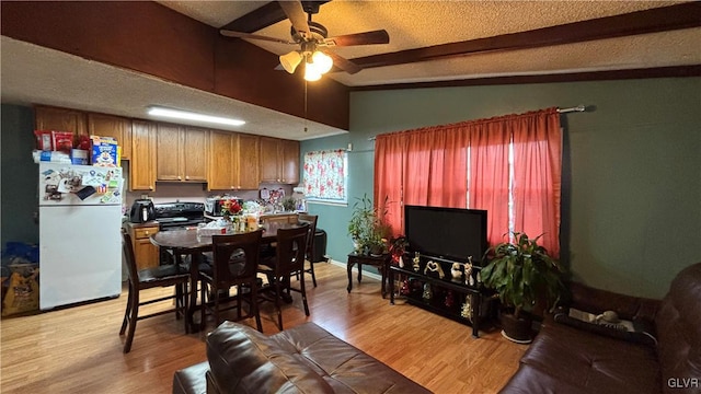 interior space featuring ceiling fan, vaulted ceiling with beams, a textured ceiling, and light hardwood / wood-style floors