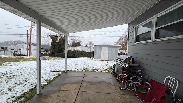 snow covered patio featuring a storage unit