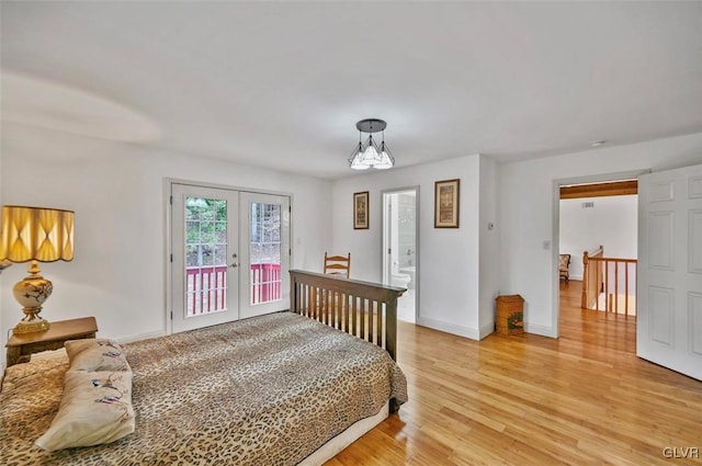 bedroom with access to exterior, french doors, light wood-type flooring, and a chandelier