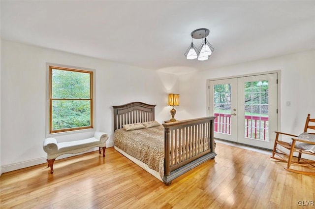 bedroom featuring access to exterior, french doors, wood-type flooring, and multiple windows