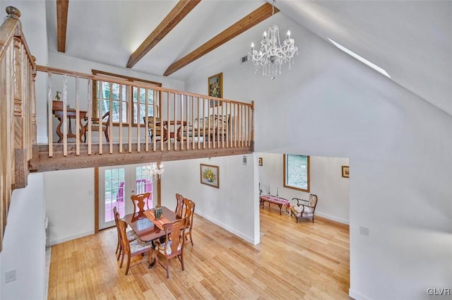 dining room featuring a chandelier, wood-type flooring, a wealth of natural light, and beam ceiling