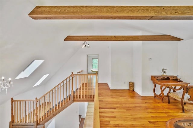 staircase featuring lofted ceiling with skylight, wood-type flooring, and a notable chandelier