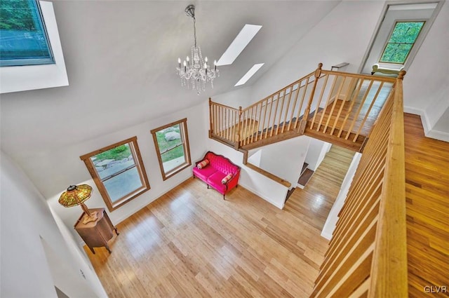 stairs featuring hardwood / wood-style flooring, lofted ceiling, a wealth of natural light, and a chandelier