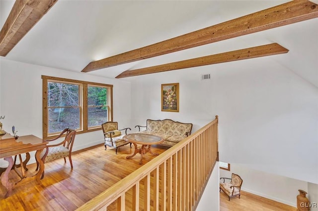 interior space featuring vaulted ceiling with beams and light hardwood / wood-style flooring