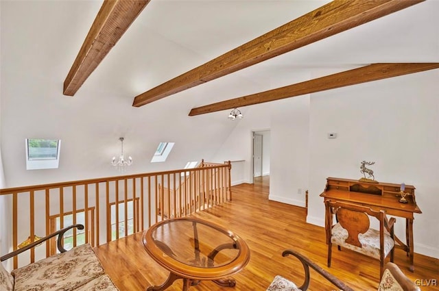 sitting room with vaulted ceiling with skylight, light hardwood / wood-style flooring, and an inviting chandelier