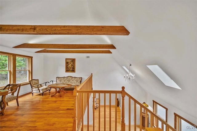 interior space with lofted ceiling with skylight, wood-type flooring, and an inviting chandelier