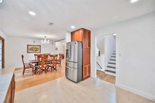 kitchen with a notable chandelier, stainless steel fridge, light tile patterned flooring, and hanging light fixtures