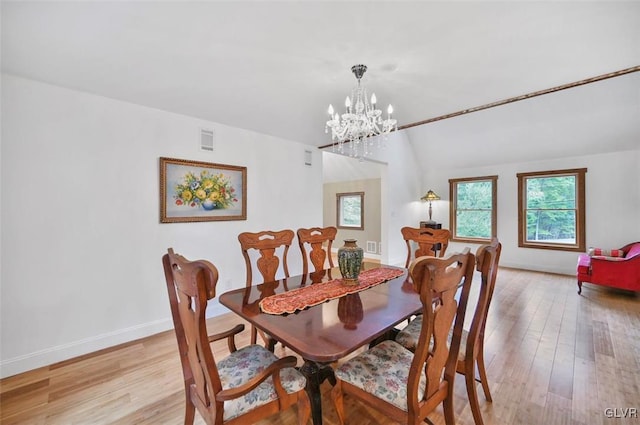 dining area with light hardwood / wood-style flooring, lofted ceiling, and an inviting chandelier