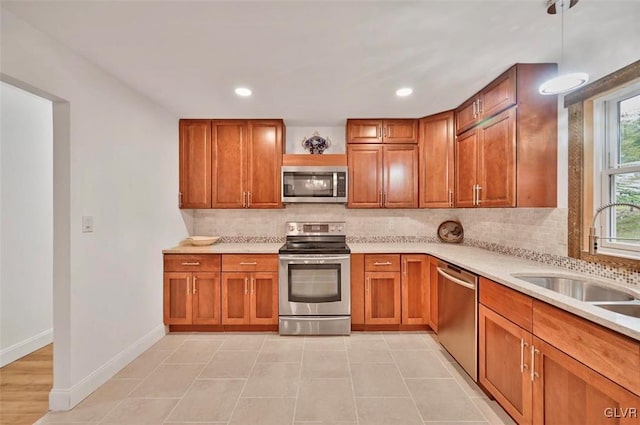 kitchen with sink, appliances with stainless steel finishes, tasteful backsplash, decorative light fixtures, and light tile patterned flooring