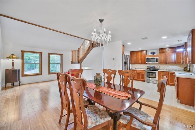 dining area featuring light hardwood / wood-style floors, sink, and a chandelier