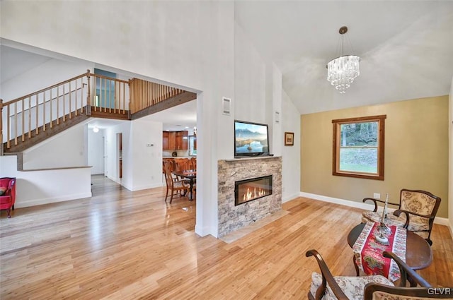 living room with a fireplace, high vaulted ceiling, a chandelier, and light hardwood / wood-style flooring