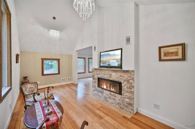 living room with a stone fireplace, wood-type flooring, and high vaulted ceiling