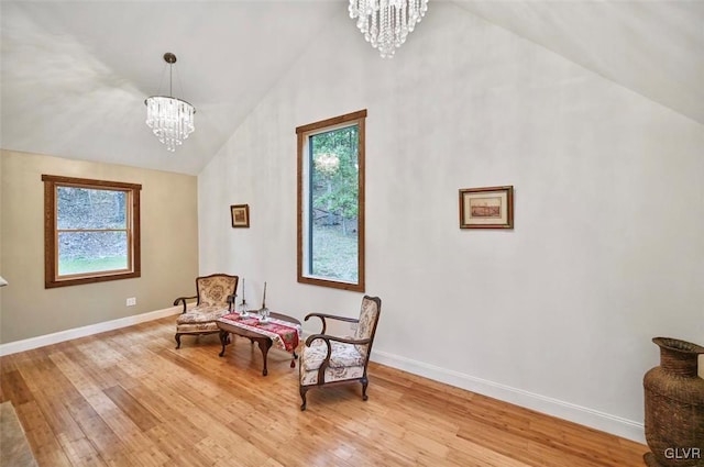 living area featuring light wood-type flooring, high vaulted ceiling, and a notable chandelier