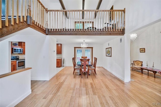 dining room with a towering ceiling, light wood-type flooring, and a notable chandelier