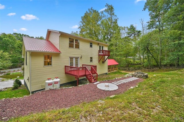 back of house with a lawn, a balcony, and a wooden deck