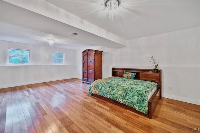 bedroom with hardwood / wood-style flooring and a notable chandelier