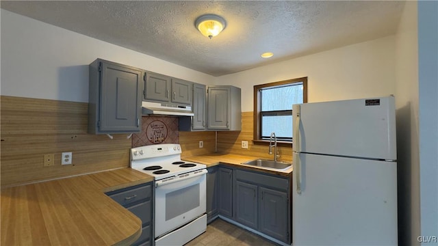 kitchen with a textured ceiling, gray cabinetry, sink, and white appliances