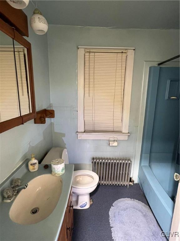 bathroom with a shower, vanity, toilet, and radiator