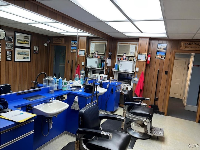 home office featuring a paneled ceiling, sink, and wooden walls