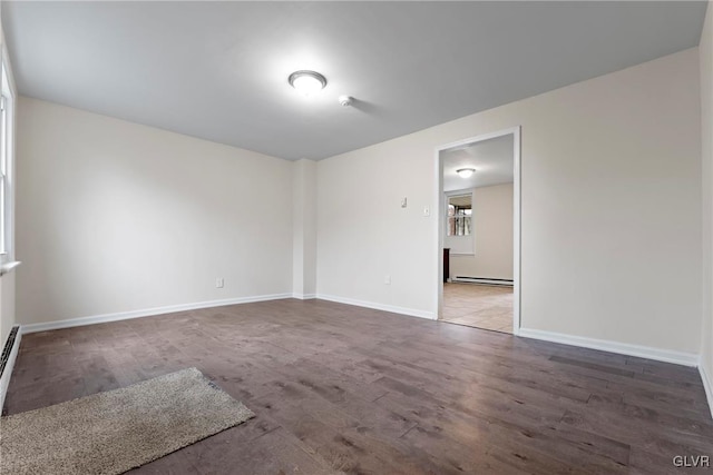 empty room with a baseboard heating unit and hardwood / wood-style flooring