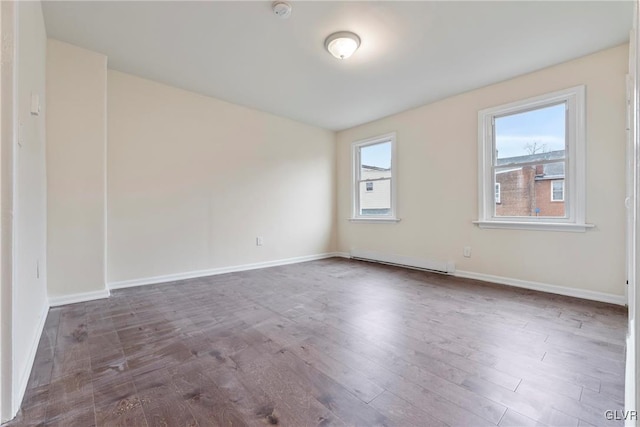 spare room featuring dark wood-type flooring, plenty of natural light, and a baseboard radiator