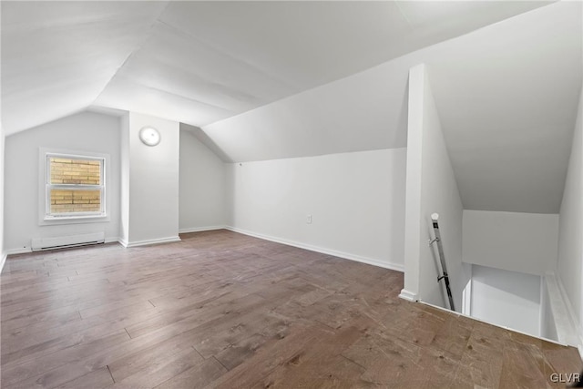 additional living space featuring wood-type flooring, vaulted ceiling, and baseboard heating