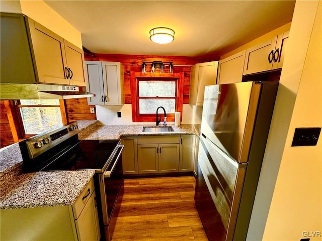 kitchen featuring electric stove, sink, stainless steel fridge, light hardwood / wood-style floors, and light stone counters