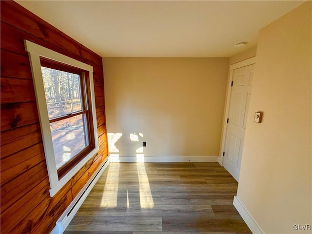 unfurnished room with hardwood / wood-style floors and baseboard heating