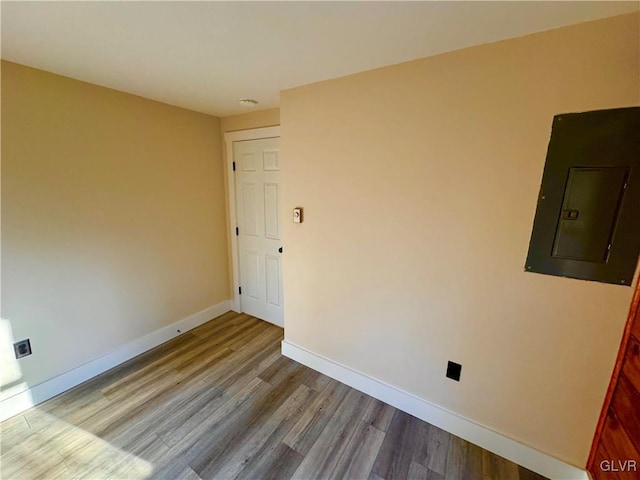 unfurnished room featuring electric panel and light hardwood / wood-style floors