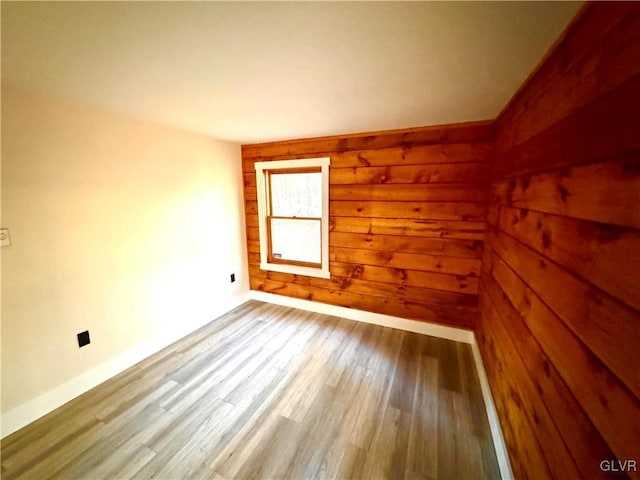 spare room featuring wood-type flooring and wood walls