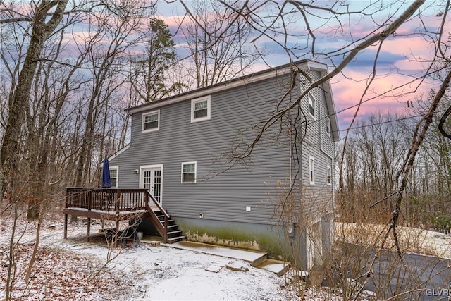 snow covered rear of property featuring a wooden deck