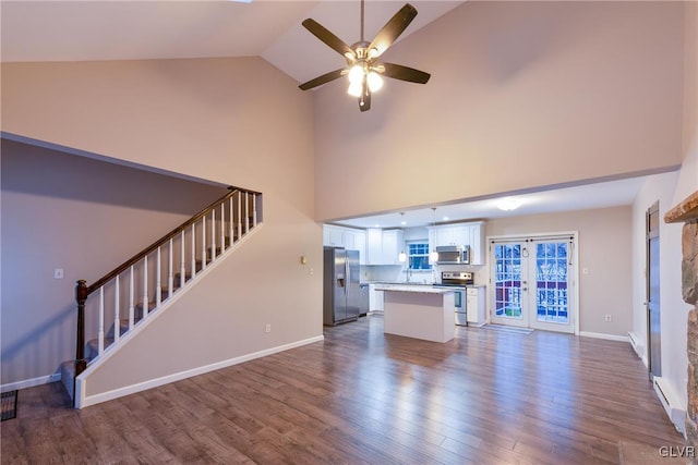 unfurnished living room with ceiling fan, dark wood-type flooring, and high vaulted ceiling