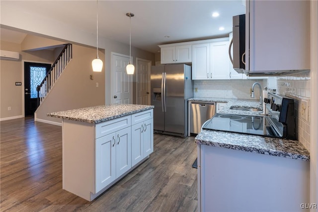 kitchen with a center island, backsplash, white cabinets, decorative light fixtures, and stainless steel appliances