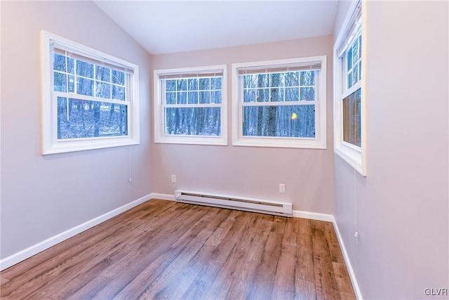 spare room featuring plenty of natural light, hardwood / wood-style floors, a baseboard radiator, and vaulted ceiling