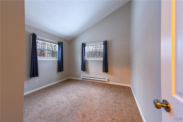 carpeted empty room featuring plenty of natural light, vaulted ceiling, and a baseboard heating unit