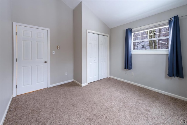 unfurnished bedroom featuring carpet flooring, vaulted ceiling, and a closet