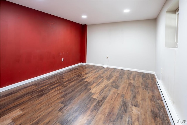 spare room with dark hardwood / wood-style flooring and a baseboard heating unit