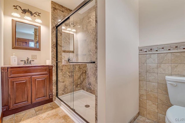 bathroom featuring walk in shower, vanity, tile walls, and toilet