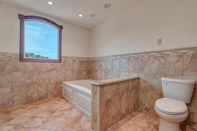 bathroom featuring a bathtub, toilet, and tile walls